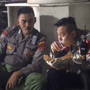 Dua Polisi Nikmati Nasi Bungkus Bersama di Dermaga Bakauheni Saat Hujan Deras